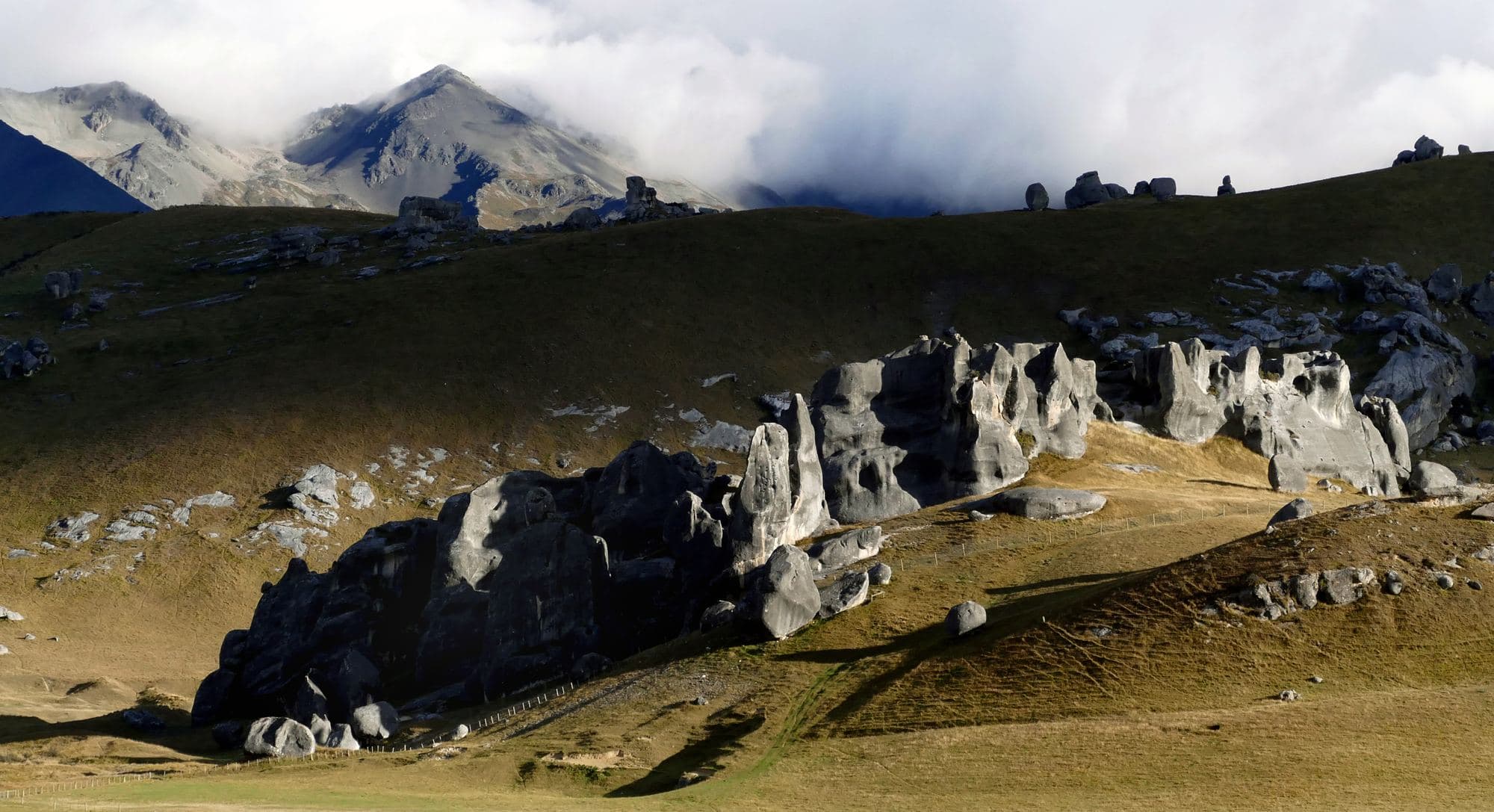 New Zealand high country: limestone outcrops below cloud-covered mountains.